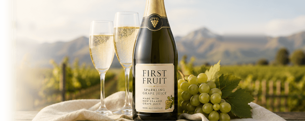 First Fruit Sparkling Grape Juice beside two filled flutes and fresh green grapes in a New Zealand vineyard